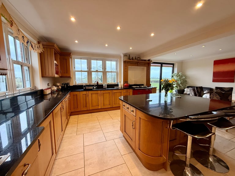 Modern kitchen with wooden cabinets, black granite countertops, island, and open layout connecting to dining area