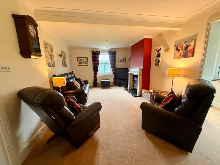 Spacious living room with two black leather recliners facing each other, fireplace, red accent wall, and warm lighting